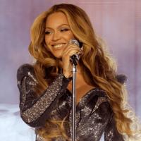 Beyoncé in a silver and black outfit smiling on stage